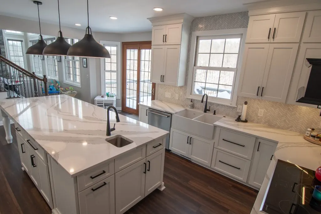 White kitchen with farmhouse sink, quartz island and black pendant lights