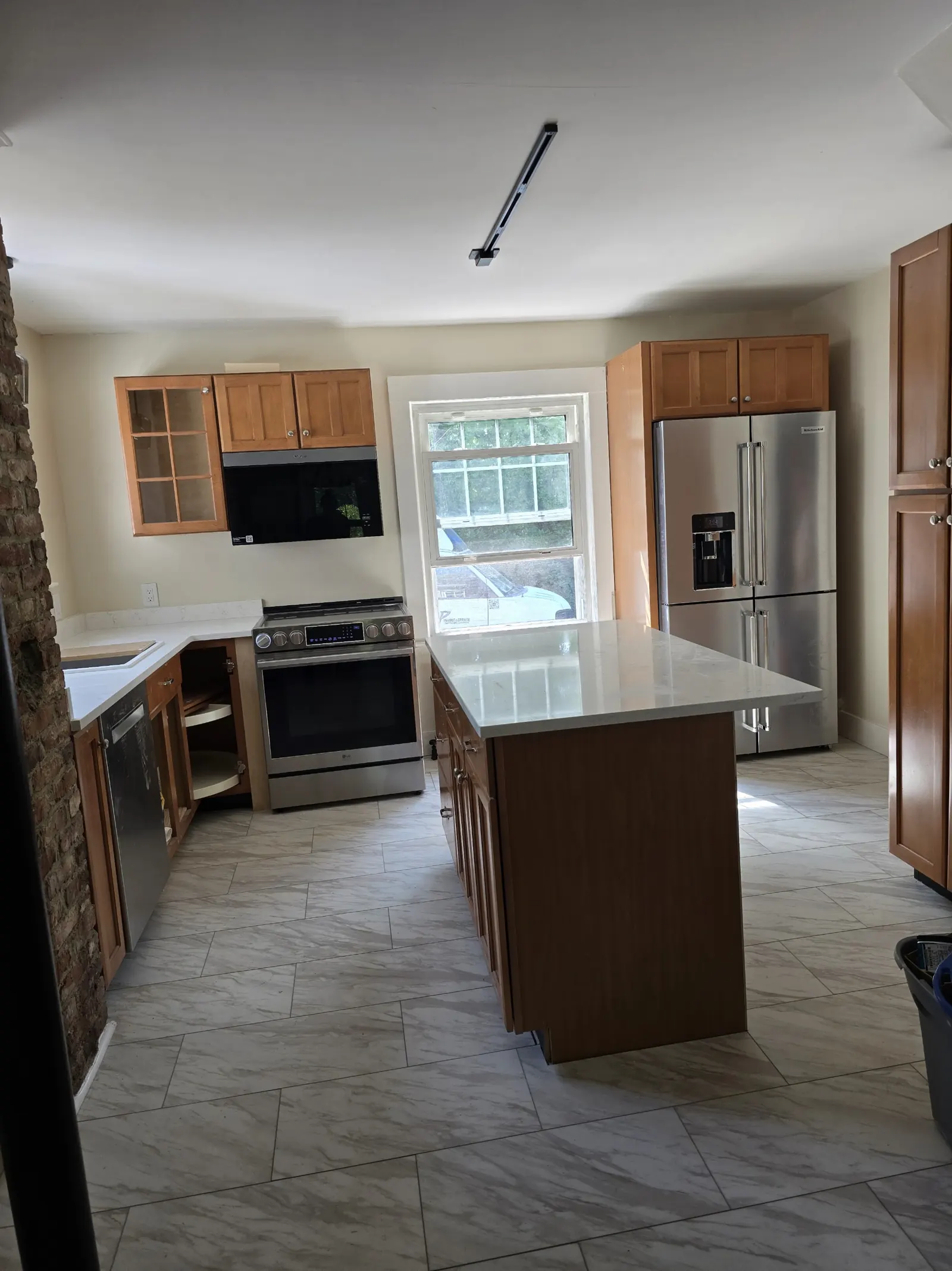 Kitchen with new island, quartz counters and large-format tile floor