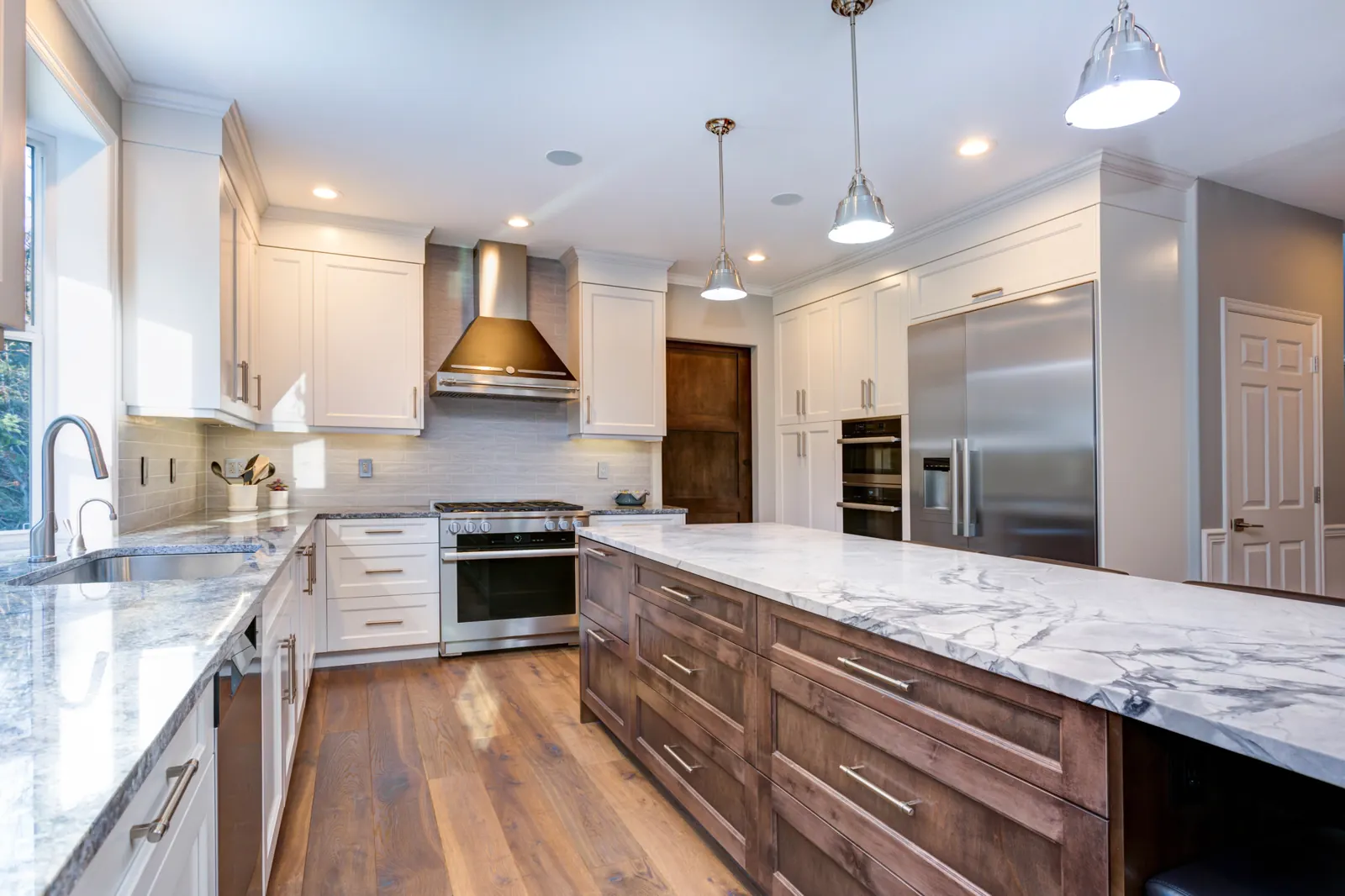 Remodeled kitchen with a long walnut-stained island, white quartz counters and stainless appliances
