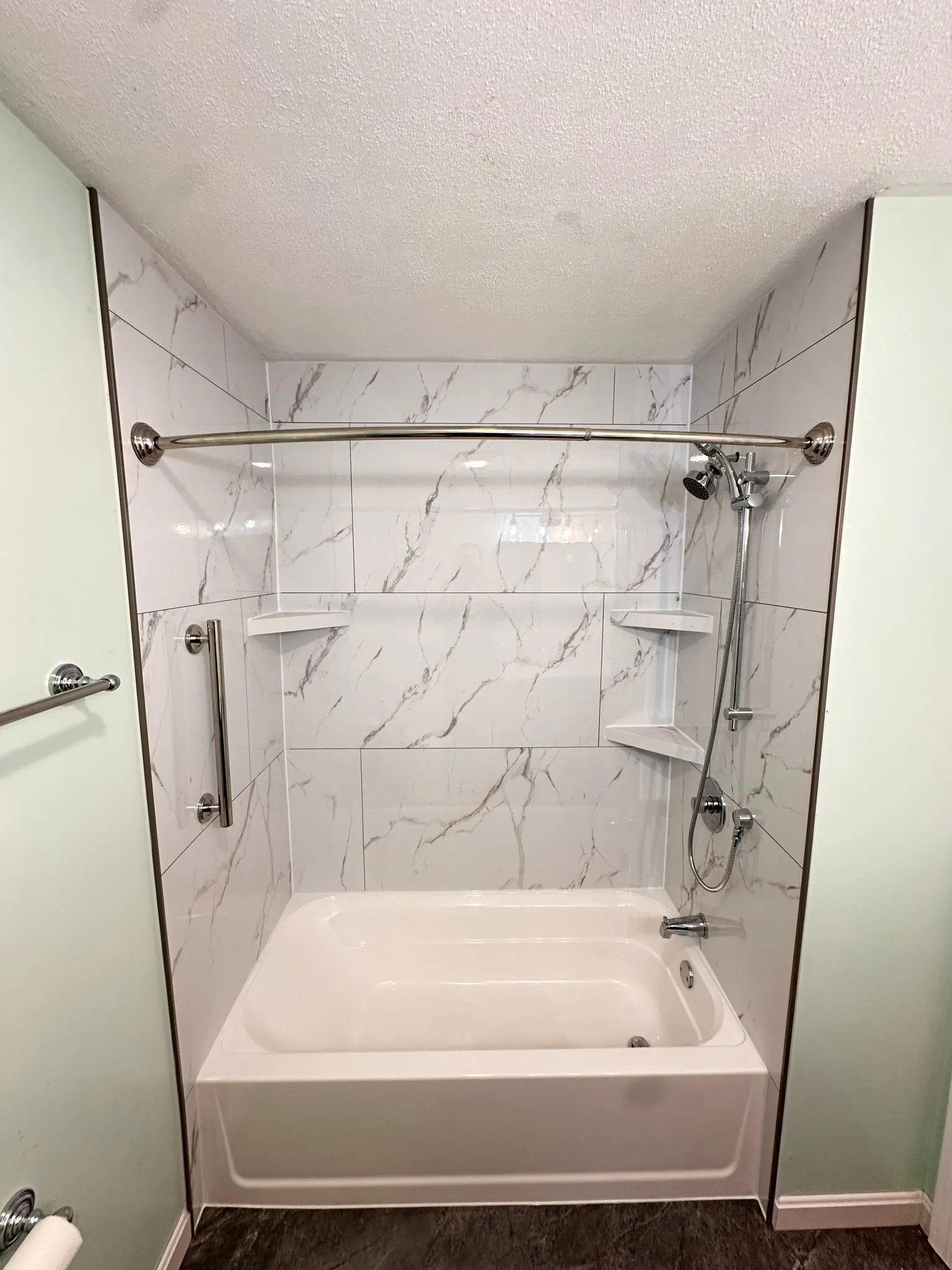 New bathtub and shower surround with white marble-look walls