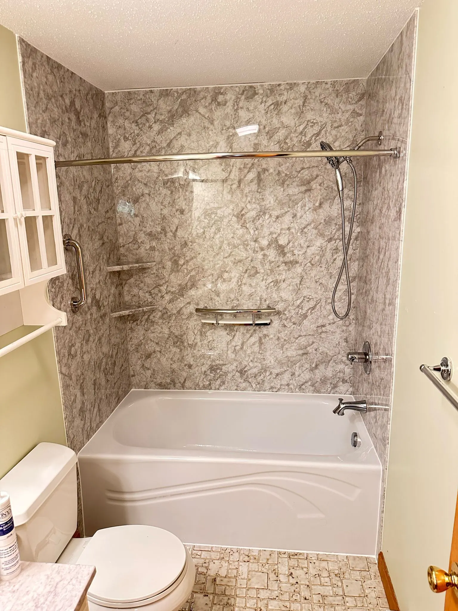 Bathtub with stone-look wall surround and chrome fixtures