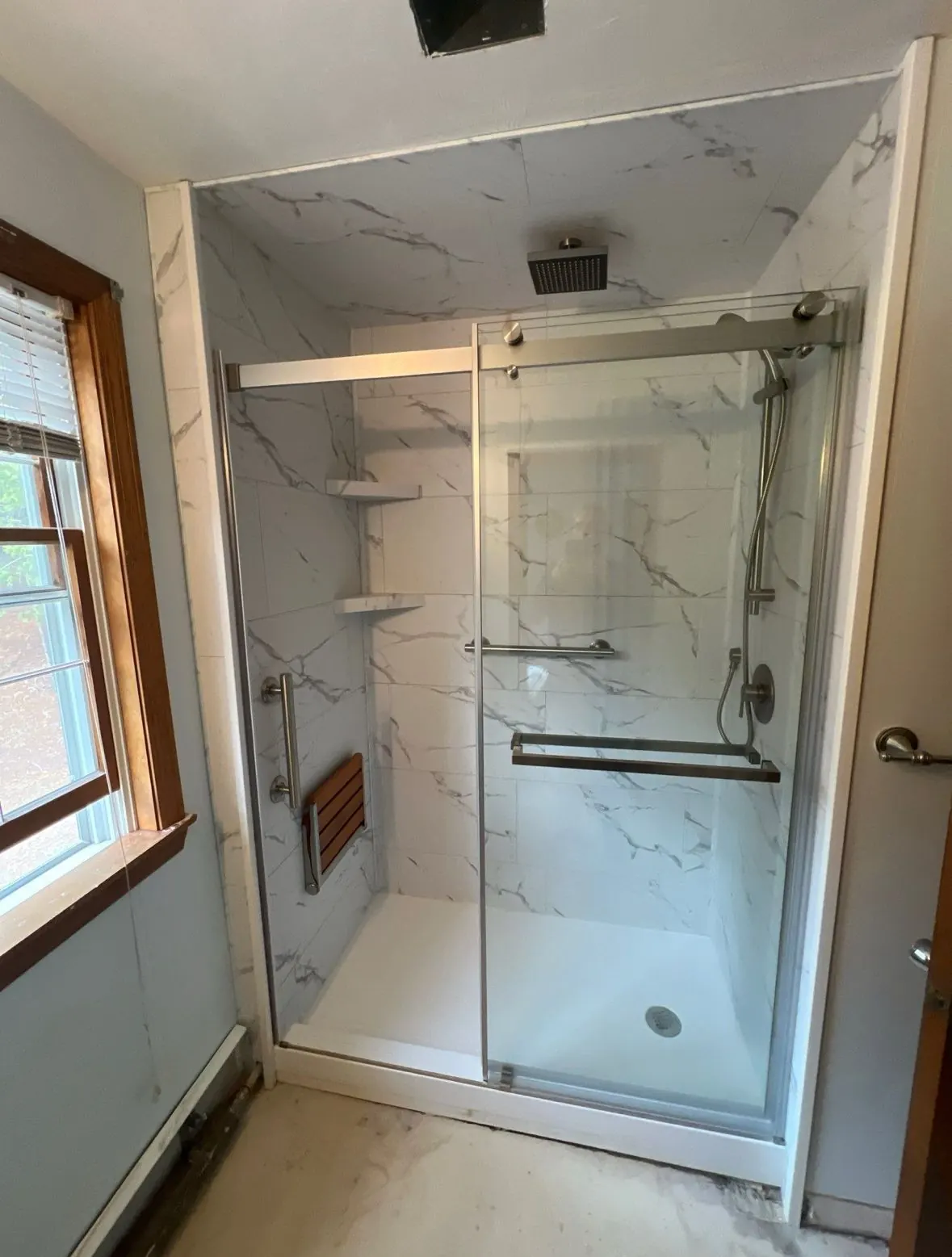 Walk-in shower with fold-down teak seat and marble-look walls