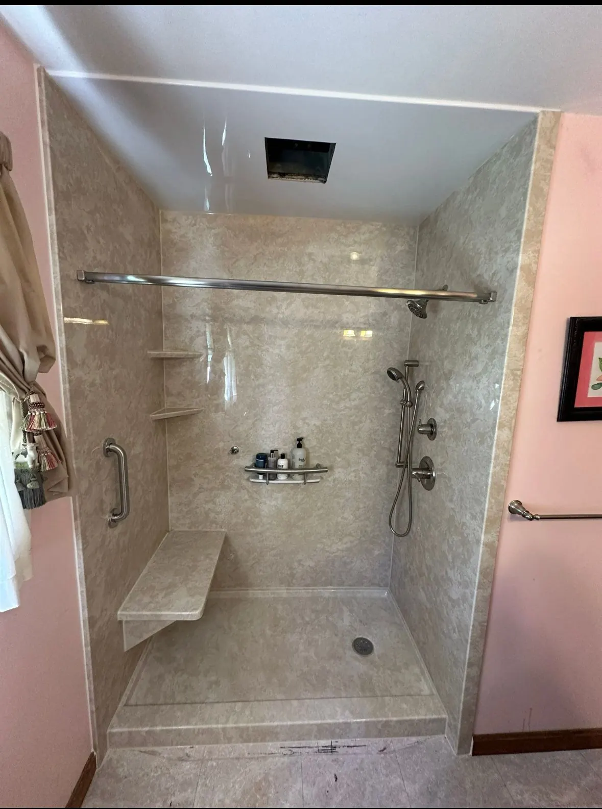 Walk-in shower with stone-look walls, built-in seat, grab bar and corner shelves