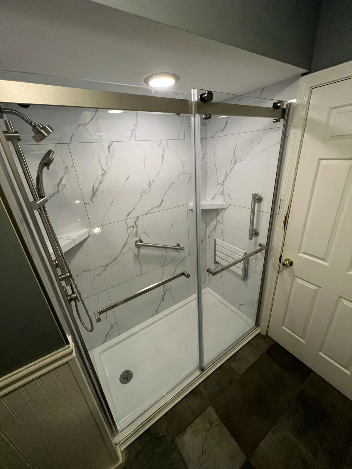 Walk-in shower with sliding glass door and grab bars